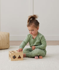 Toddler playing with wooden toy, wearing an ergoPouch Long Sleeve Pajamas 1.0 TOG Willow
