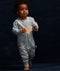Toddler dressed in a light grey, long-sleeved one-piece romper adorned with a delicate white leaf pattern. The romper features a central zipper and ribbed cuffs at the ankles.