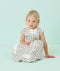 Infant wearing a white sleeveless sleep sack featuring a wave pattern, sitting against a light blue background.
