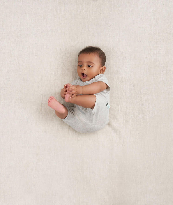 Newborn rolling in ergoPouch Short Sleeve Romper 0.2 TOG Grey Marle, perfect for the summer