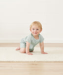 Infant crawling wearing a ergoPouch Short Sleeve Romper in Sage