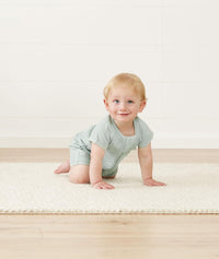 Infant crawling wearing a ergoPouch Short Sleeve Romper in Sage