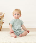Infant sitting, wearing an ergoPouch Short Sleeve Romper 0.2 TOG Sage