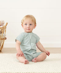 Infant sitting, wearing an ergoPouch Short Sleeve Romper 0.2 TOG Sage