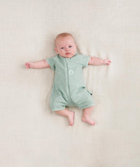 Baby lying wearing a ergoPouch Short Sleeve Romper in Sage