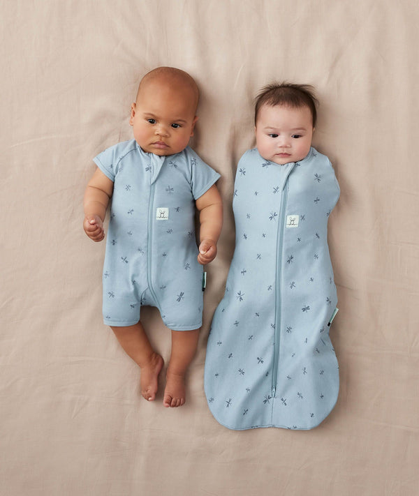 Two newborns wearing ergoPouch Cocoon Swaddle Sack 0.2 TOG and Short Sleeve Romper in Dragonflies