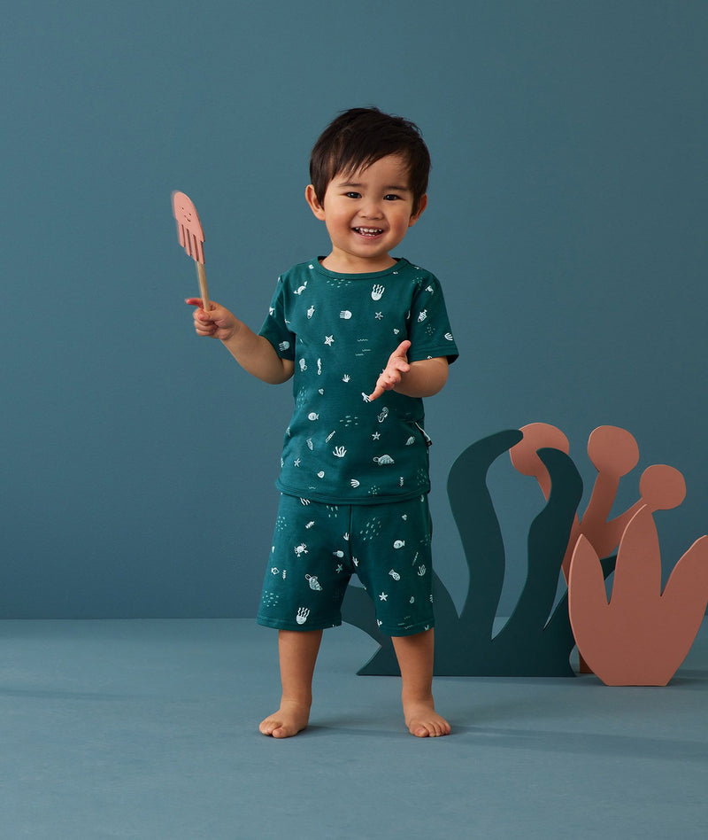 Toddler holding a toy, wearing an ergoPouch Short Sleeve Pajamas 0.2 TOG Ocean Blue