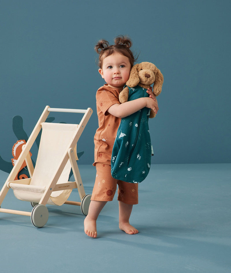 Child hugging a doll in ergoPouch Short Sleeve Pajamas 0.2 TOG Sunny, perfect for the summer