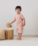 Toddler holding wooden toys, wearing an ergoPouch Short Sleeve Pajamas 0.2 TOG Daisies