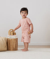 Toddler holding wooden toys, wearing an ergoPouch Short Sleeve Pajamas 0.2 TOG Daisies