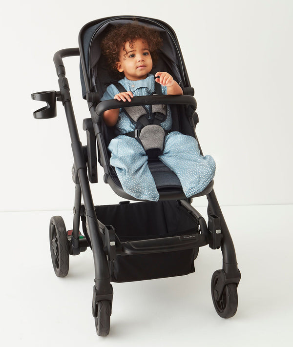 Child sitting in a pram wearing an ergoPouch Sleep Suit Sack 3.5 TOG Night Sky