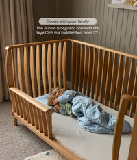 Toddler lying on the ergoPouch ellska Skye Crib that has converted into a toddler bed, made to grow with your family.