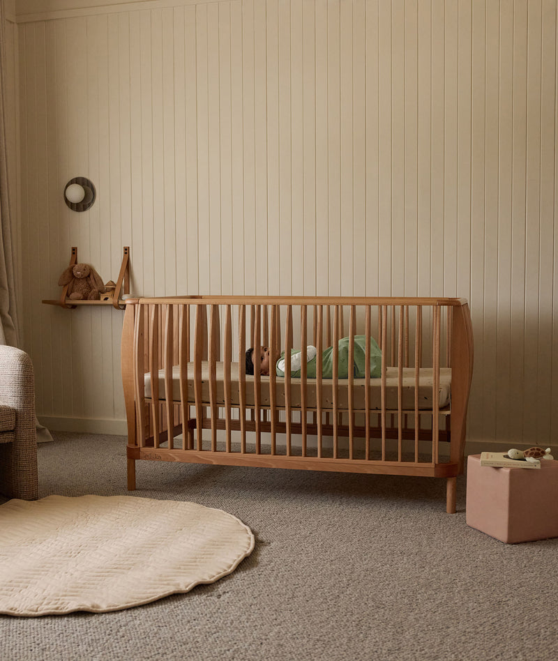 Baby lying in the new ergoPouch ellska Skye Crib, a promise of safety and serenity