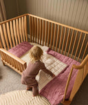 Toddler getting into their ergoPouch ellska Skye Crib that has converted into a toddler bed, made to grow with your family