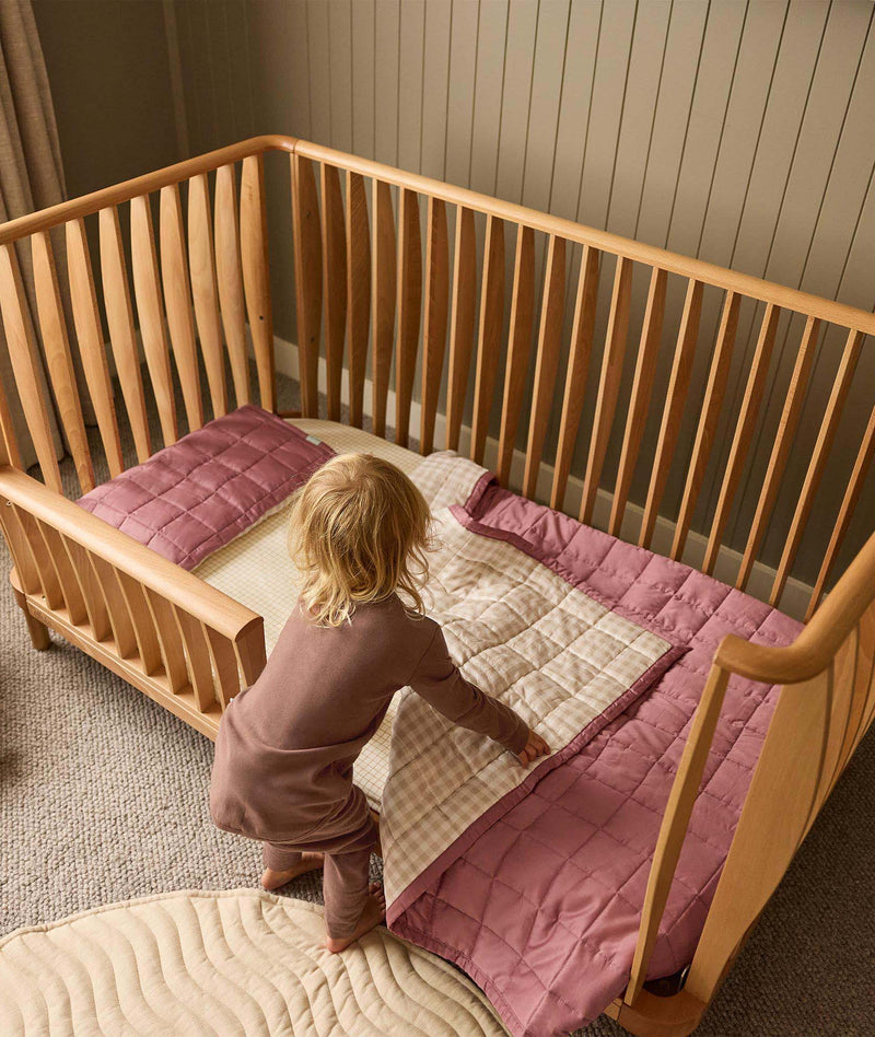 Toddler getting into their ergoPouch ellska Skye Crib that has converted into a toddler bed, made to grow with your family