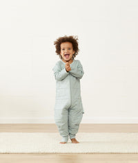 Happy child in a warm ergoPouch Sleep Onesie 3.5 TOG Sage
