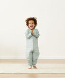 Happy child in a warm ergoPouch Sleep Onesie 2.5 TOG Sage