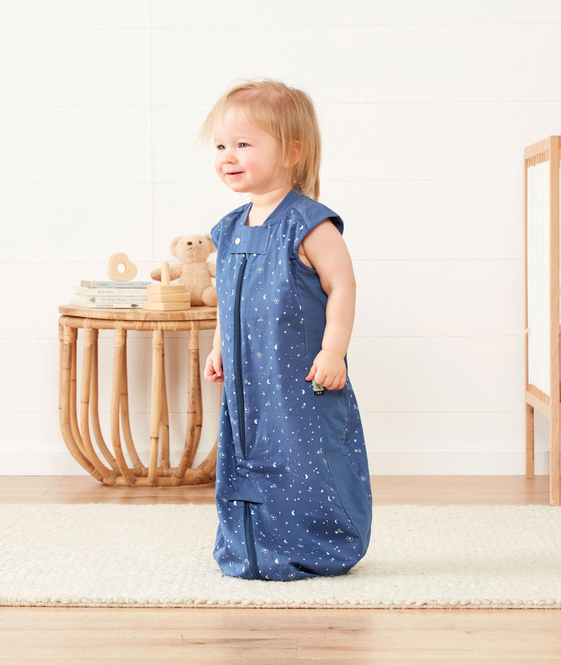 Child wearing a light ergoPouch Sleep Suit Sack 0.3 TOG Night Sky, a sleep sack with legs