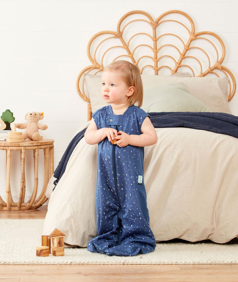 Child wearing a light ergoPouch Sleep Suit Sack 0.3 TOG Night Sky, a sleep sack with legs