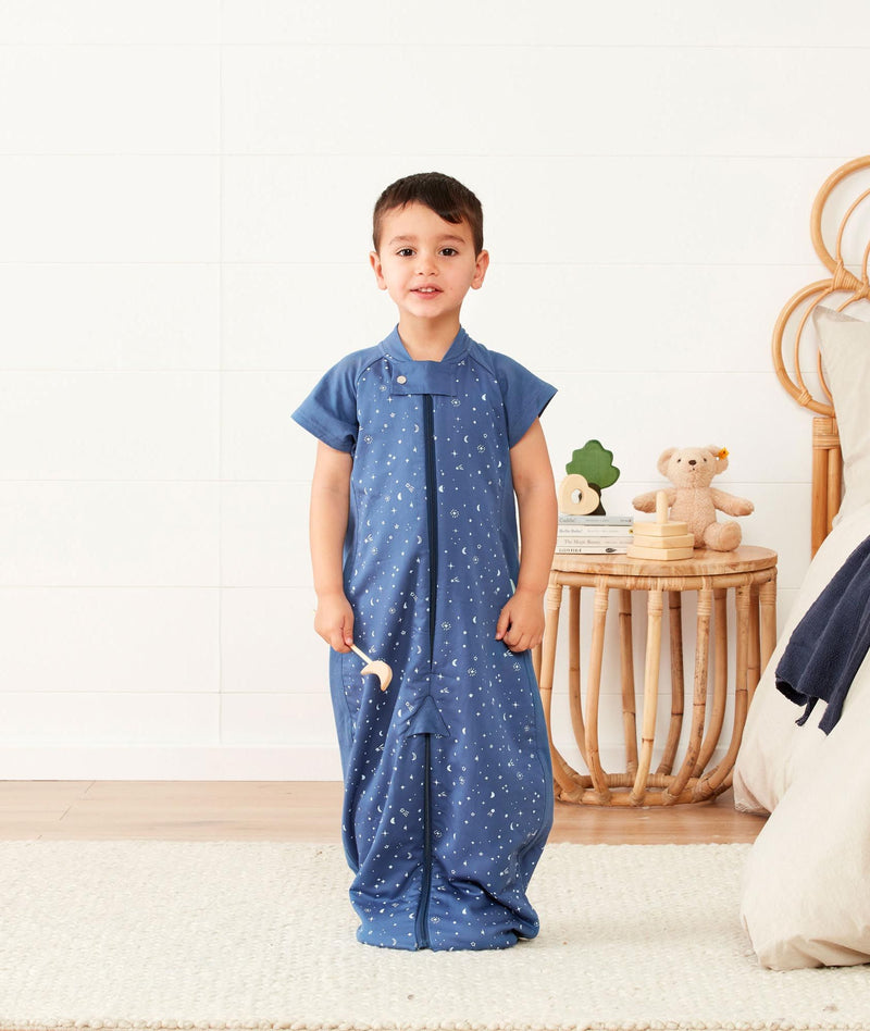 Smiling child in ergoPouch Sleep Suit Sack 1.0 TOG Night Sky, a sleep sack with legs