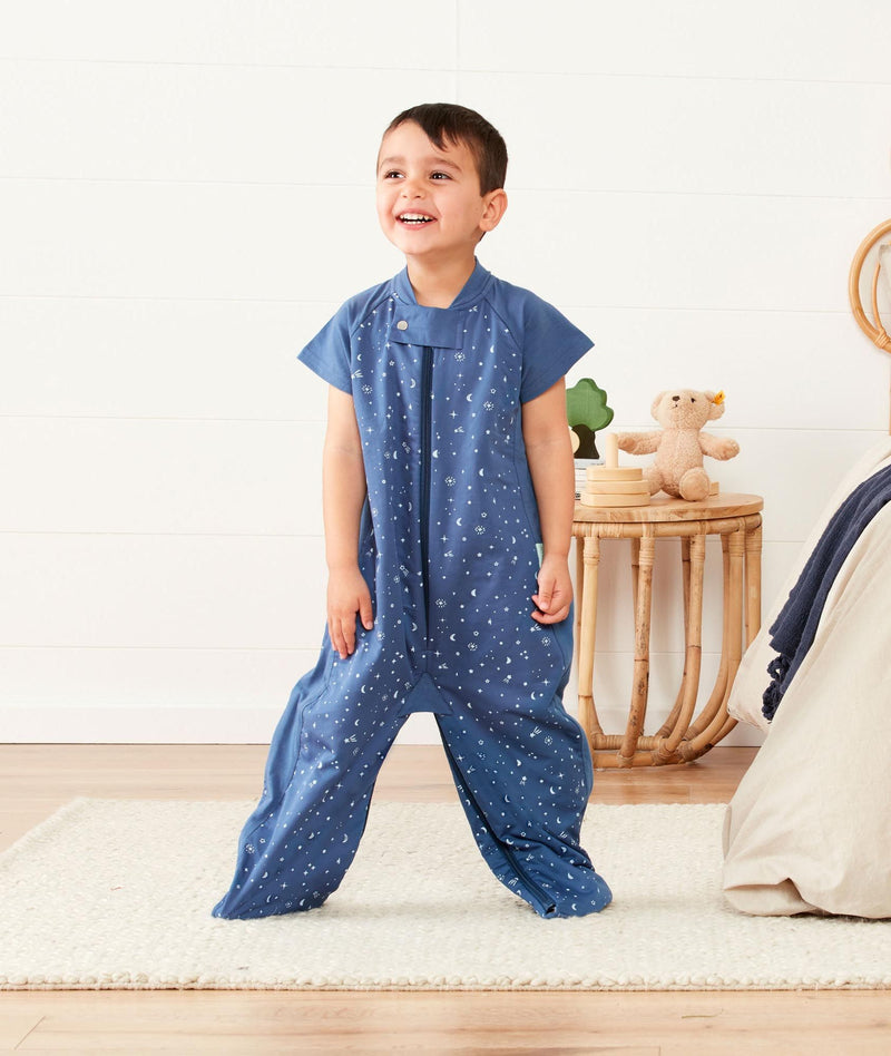 Two kids wearing in an ergoPouch Sleep Suit Sack 1.0 TOG Night Sky, a sleeping bag that converts to a sleeping bag with legs