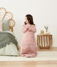 Child sitting in an ergoPouch Sleep Suit Sack 3.5 TOG Berries, a warm sleeping bag that converts to a sleeping bag with legs