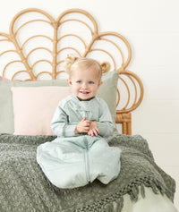 Toddler smiling wearing ergoPouch Sleep Suit Sack in Sage