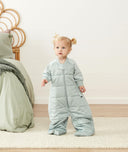 Smiling child in ergoPouch Sleep Suit Sack 3.5 TOG Sage, a warm sleep sack with legs
