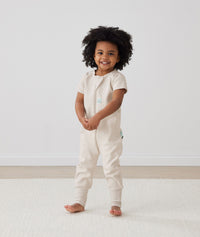 Toddler standing in ergoPouch Sleep Onesie 1.0 TOG Oatmeal Marle