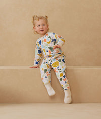 Toddler sitting, wearing an ergoPouch Sleep Onesie 2.5 TOG Fruit Salad