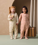 Two preschoolers are holding each other's hands, both wearing ergoPouch Sleep Onesie 2.5 TOG in Savannah and Elephant Parade colorways.