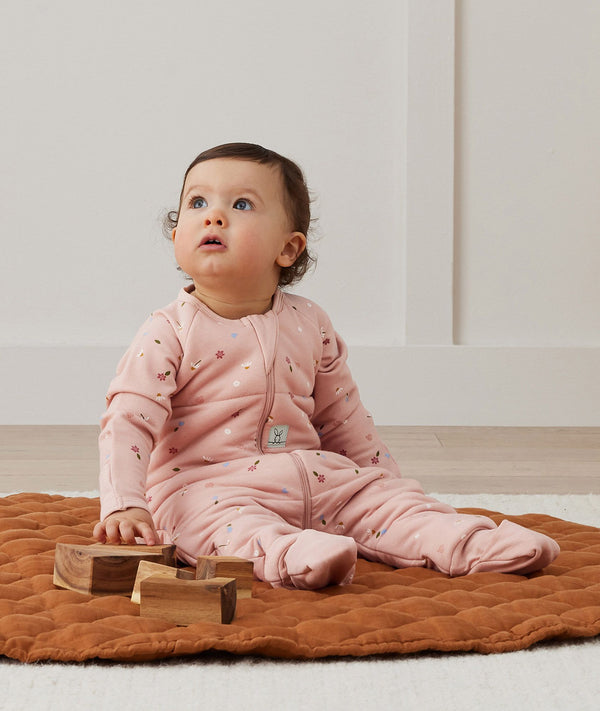 Infant baby sitting, wearing a TOG-rated ergoPouch Sleep Onesie Daisies