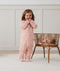 Toddler playing with baby doll in bassinet, wearing an ergoPouch Sleep Onesie 2.5 TOG Daisies