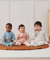 Three infants sitting wearing ergoPouch Sleep Onesie 3.5 TOG Daisies, Dragonflies, and Oatmeal Marle