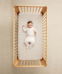 Child lying in crib wearing an ergoPouch Sleep Onesie 2.5 TOG Oatmeal Marle