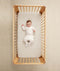 Child lying in crib wearing an ergoPouch Sleep Onesie 2.5 TOG Oatmeal Marle