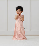 Child standing in ergoPouch Jersey Sleep Suit Sack 0.2 TOG Daisies, a light sleeping bag that converts to a sleeping bag with legs