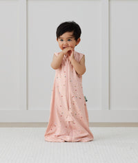 Child standing in ergoPouch Jersey Sleep Suit Sack 0.2 TOG Daisies, a light sleeping bag that converts to a sleeping bag with legs