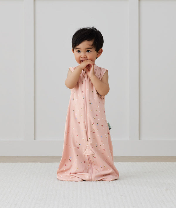 Child standing in ergoPouch Jersey Sleep Suit Sack 0.2 TOG Daisies, a light sleeping bag that converts to a sleeping bag with legs