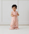 Toddler wearing an ergoPouch Sleep Suit Sack 0.2 TOG Daisies, holding a wooden toy