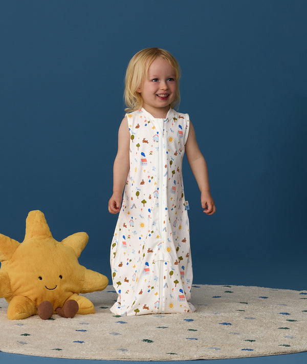 Smiling toddler wearing an ergoPouch Jersey Sleep Suit Sack  0.2 TOG Daydream, a sleeping sack that converts to a sleep suit with legs