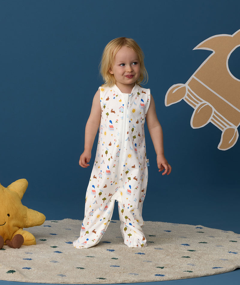 Smiling toddler wearing an ergoPouch Jersey Sleep Suit Sack  0.2 TOG Daydream, a sleeping sack that converts to a sleep suit with legs