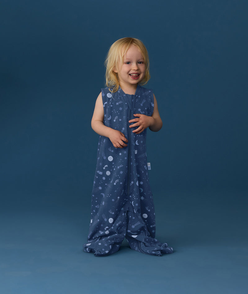Smiling toddler wearing an ergoPouch Jersey Sleep Suit Sack 0.2 TOG Starbeam, a sleep sack that converts to a sleep suit with legs.