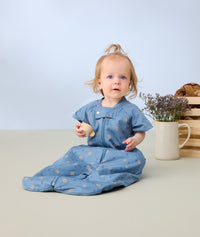 Infant sitting in on the floor wearing ergoPouch Sleep Suit Sack 1.0 TOG in Petit Pretzel