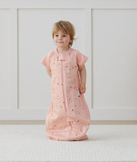 Child standing in an ergoPouch Sleep Suit Sack 1.0 TOG Daisies, a sleeping bag that converts to a sleeping bag with legs
