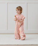 Child standing in an ergoPouch Sleep Suit Sack 1.0 TOG Daisies, a sleeping bag that converts to a sleeping bag with legs