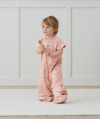 Child standing in an ergoPouch Sleep Suit Sack 1.0 TOG Daisies, a sleeping bag that converts to a sleeping bag with legs