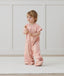 Child standing in an ergoPouch Sleep Suit Sack 1.0 TOG Daisies, a sleeping bag that converts to a sleeping bag with legs