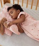 Child lying in an ergoPouch Sleep Suit Sack 1.0 TOG Daisies, a sleeping bag that converts to a sleeping bag with legs