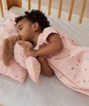 Toddler lying on ergoPouch Organic Toddler Pillow Case in Daisies cuddling a teddy